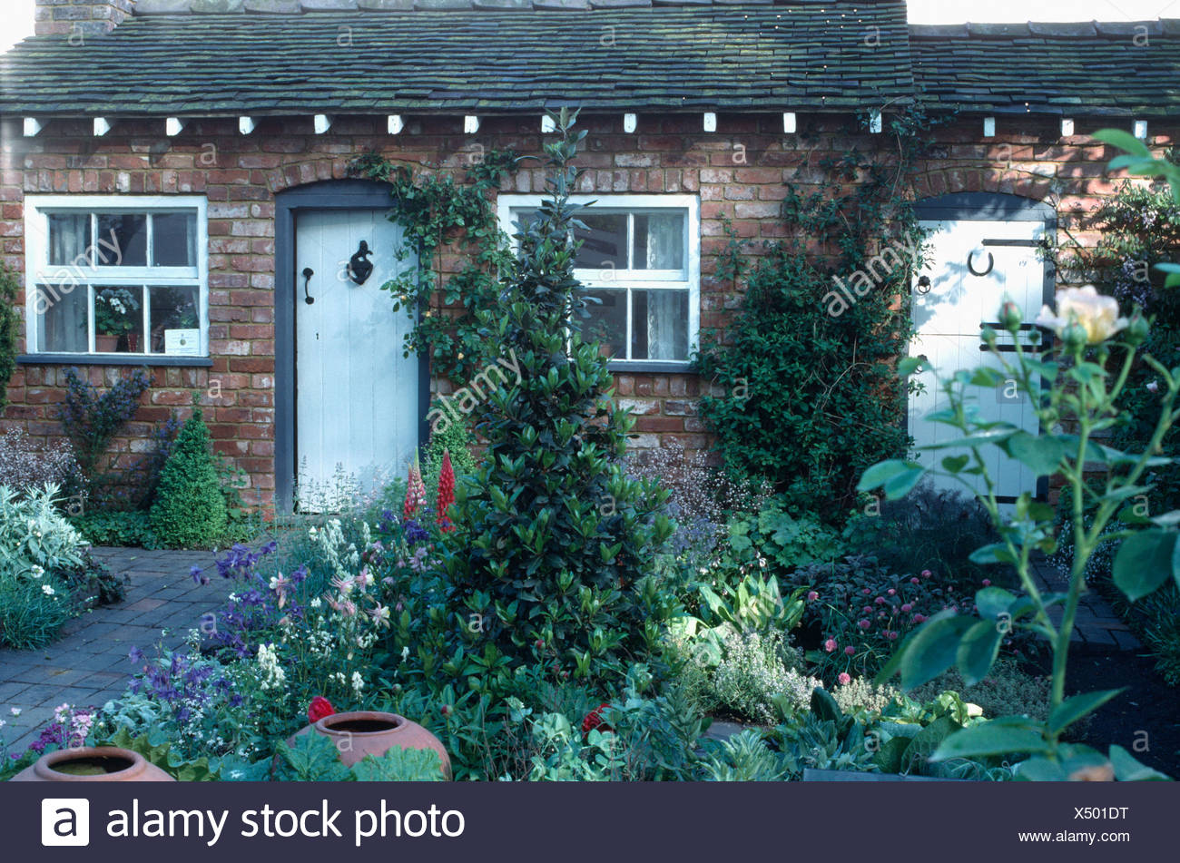 Summer Flowering Plants In Front Garden Of Small Cottage With