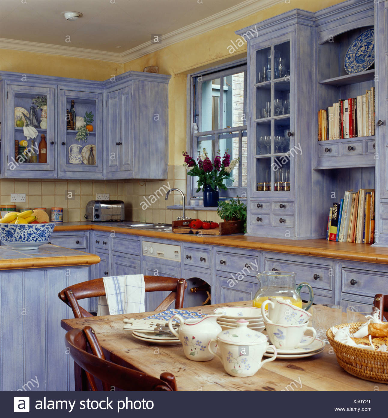 Crockery On Pine Table In Cottage Kitchen With Pale Blue