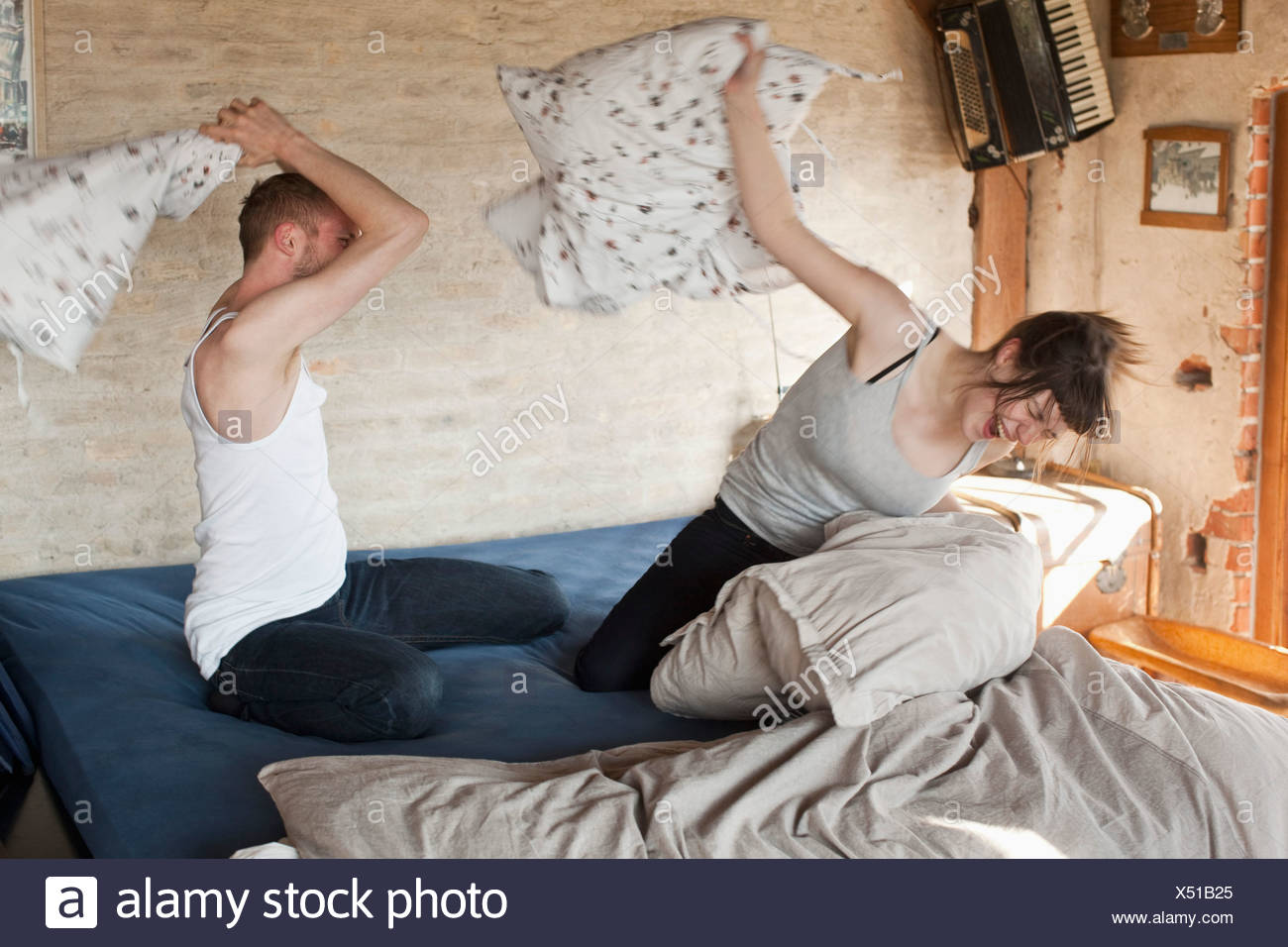 A Boyfriend And His Girlfriend Having A Pillow Fight In Bed Stock