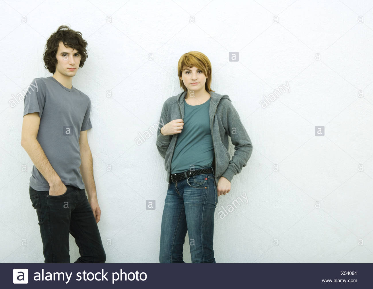 Young man and young woman leaning against wall, looking at camera, white background Stock Photo