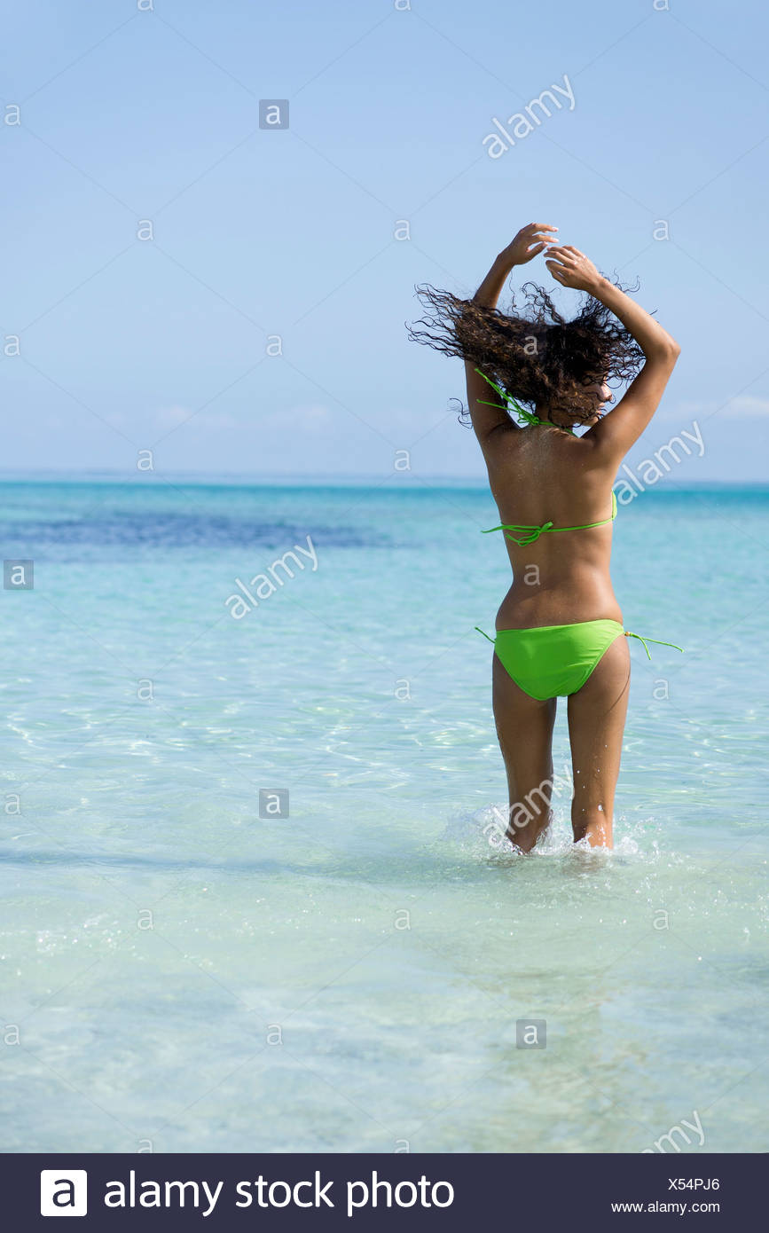 Woman In Bikini Jumping In Water With Hair Flying Stock Photo