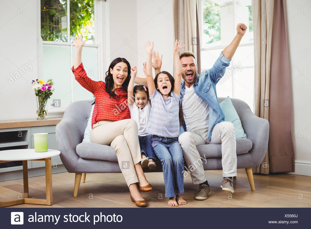 Happy Family Cheering While Siting On Sofa Stock Photo Alamy