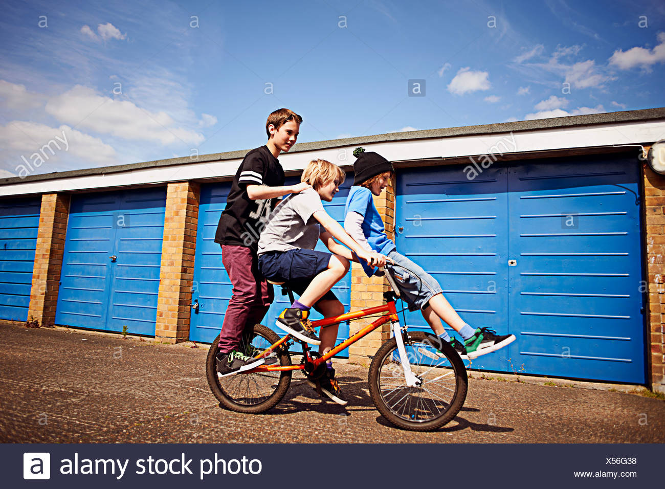 Boy giving two friends a ride on bike Stock Photo