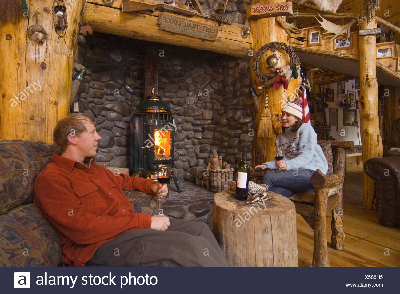 A Couple Relaxing And Drinking Wine By A Fire At A Ski Lodge Near