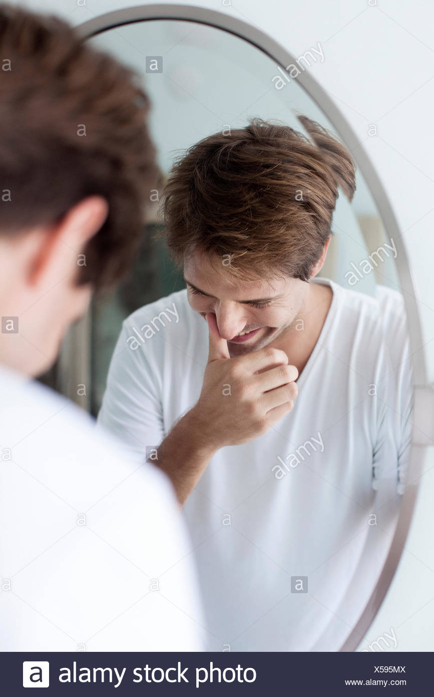 Man laughing to self, reflection in mirror Stock Photo
