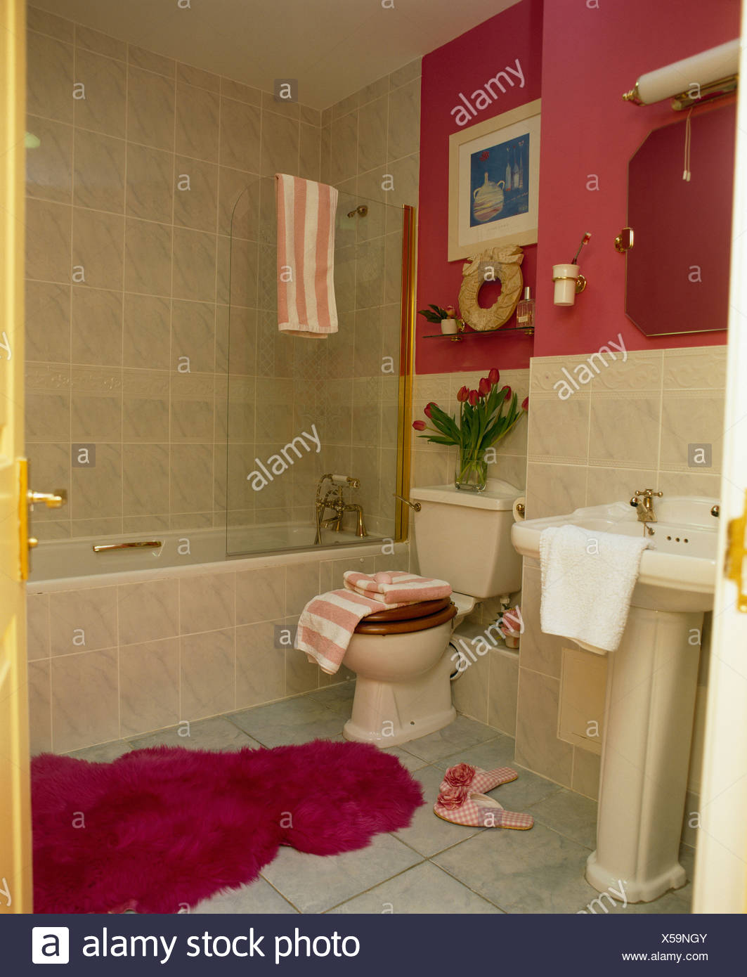 Fluffy Red Bathmat On Floor Of Red Bathroom With Cream Tiles Stock
