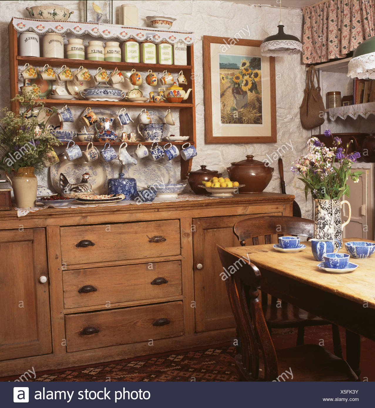 Collection Of China On Cluttered Shelves Above Pine Dresser In