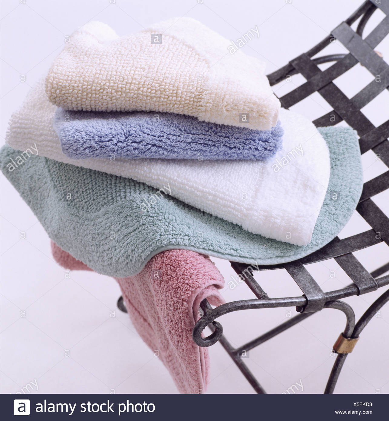 Close Up Of Pale Blue And Pink Bath Mats On Metal Chair Stock
