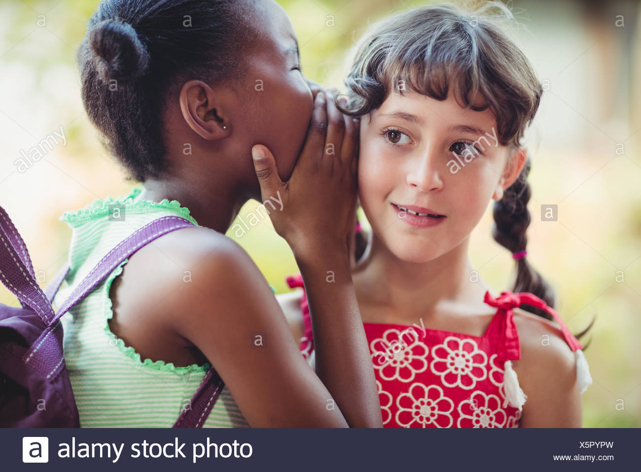 Girl telling a secret to her friend - Stock Image