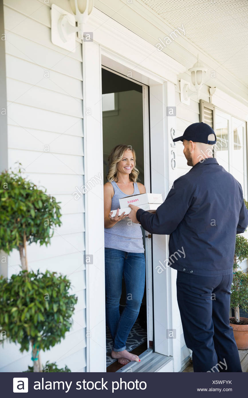 Woman Receiving Delivery At Front Door Stock Photo