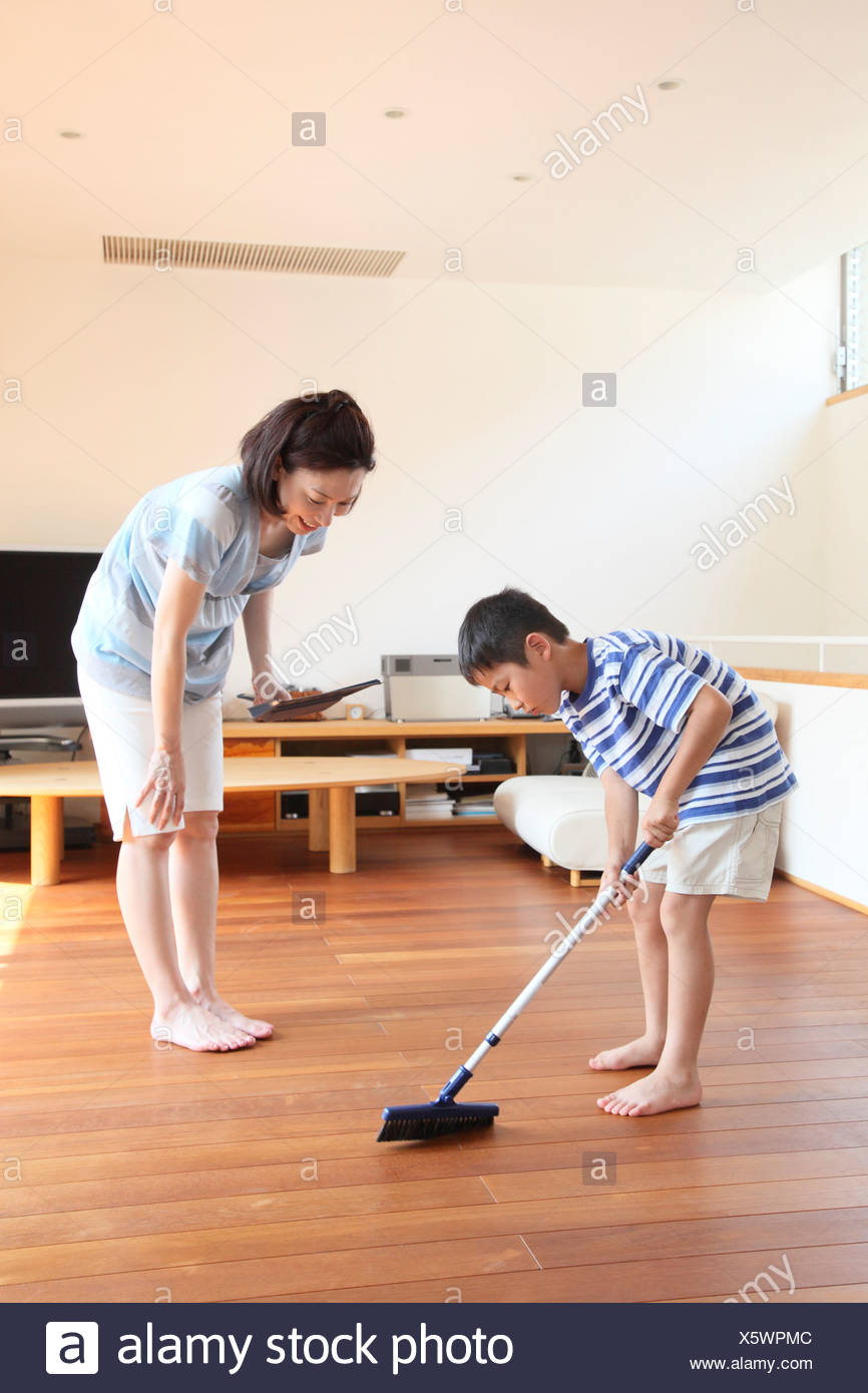 Mother And Boy Sweeping Floor With Broom And Dustpan Stock Photo