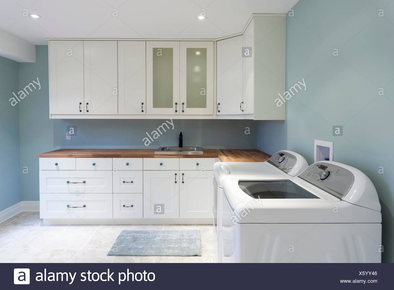 A New Residential Laundry Room With White Cabinets And Blue Walls