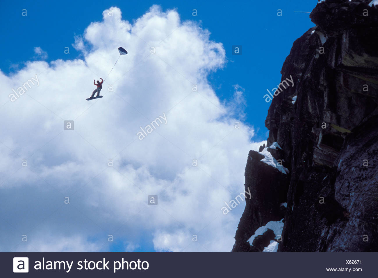 Snowboard-BASE jumper doing a backflip off a cliff near Lake Tahoe. Stock Photo