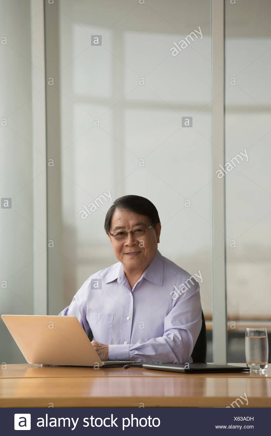 Singapore Senior Businessman Using Laptop At Desk Stock Photo