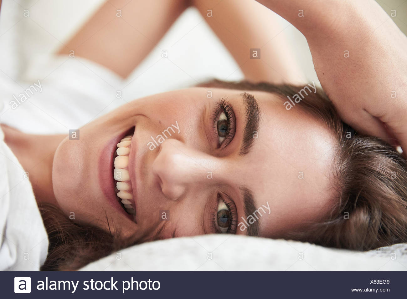 Close up portrait of beautiful young woman lying on bed Stock Photo