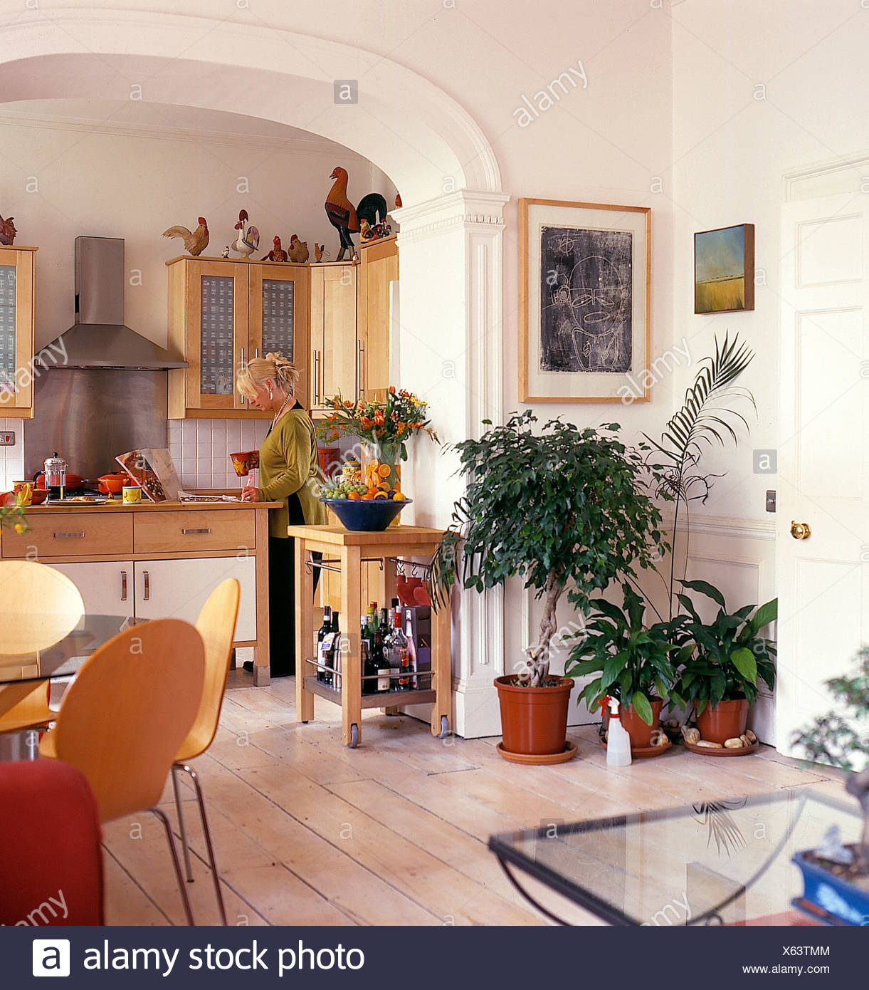 Blonde Haired Woman In Townhouse Kitchen With Lush Green