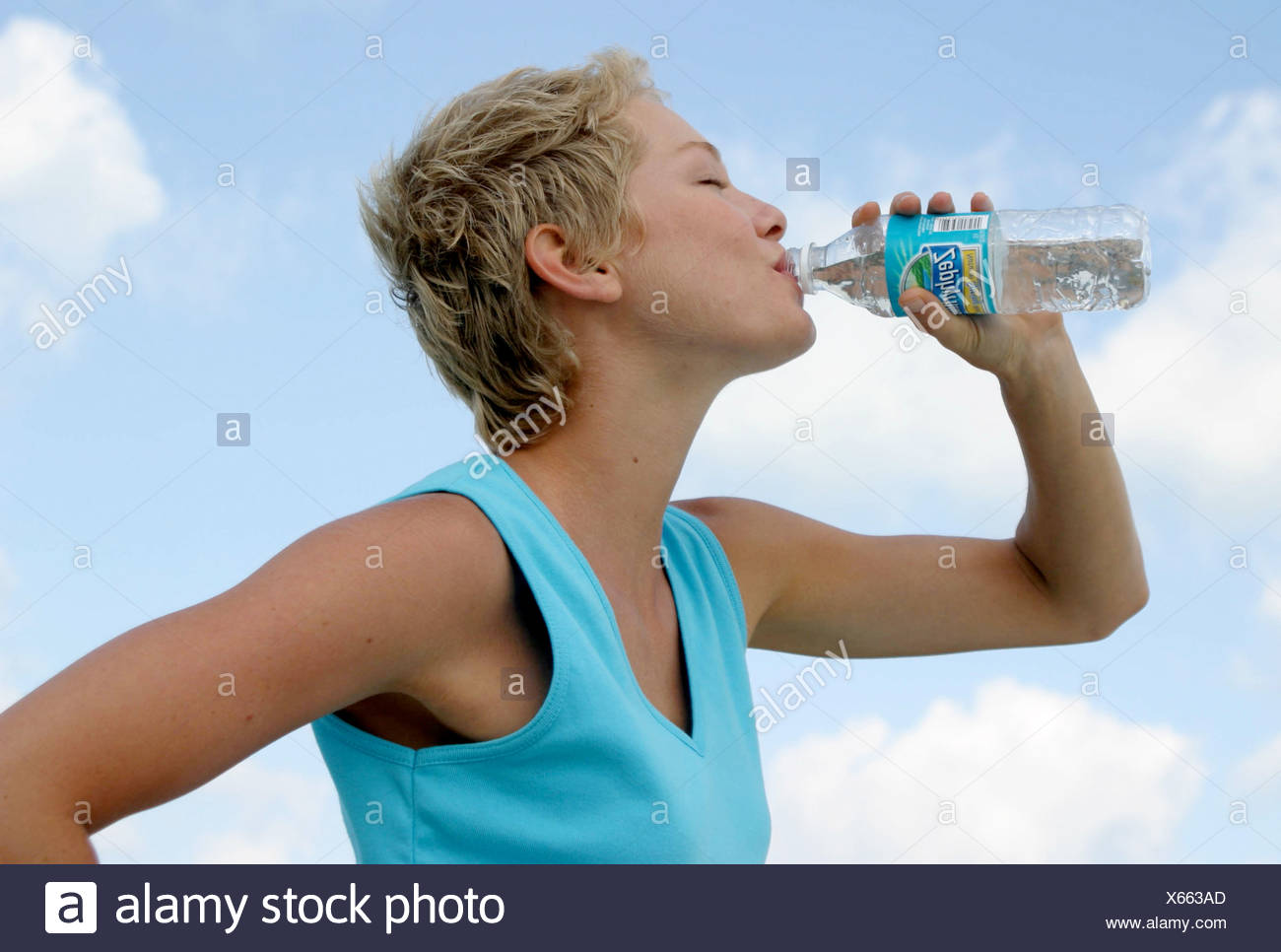 Female Short Blonde Hair Wearing Turquoise Vest Top Drinking From