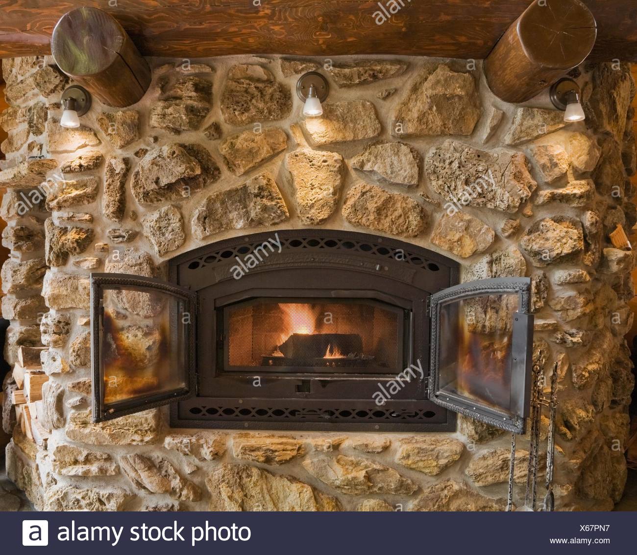 Lit Fieldstone And Rock Fireplace In Living Room In Cedar Log Home