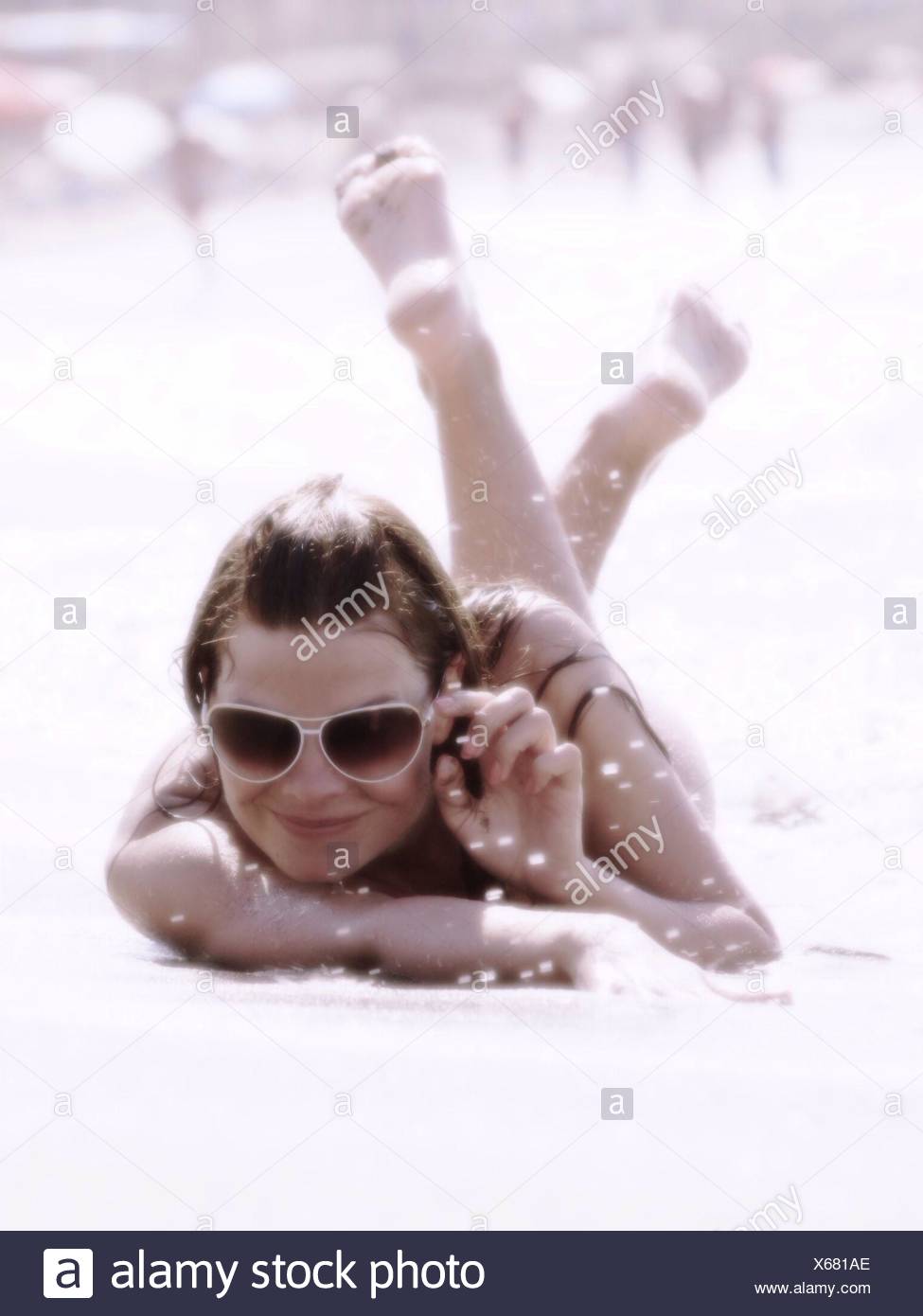 Portrait Of A Happy Young Woman Lying On Beach Stock Photo