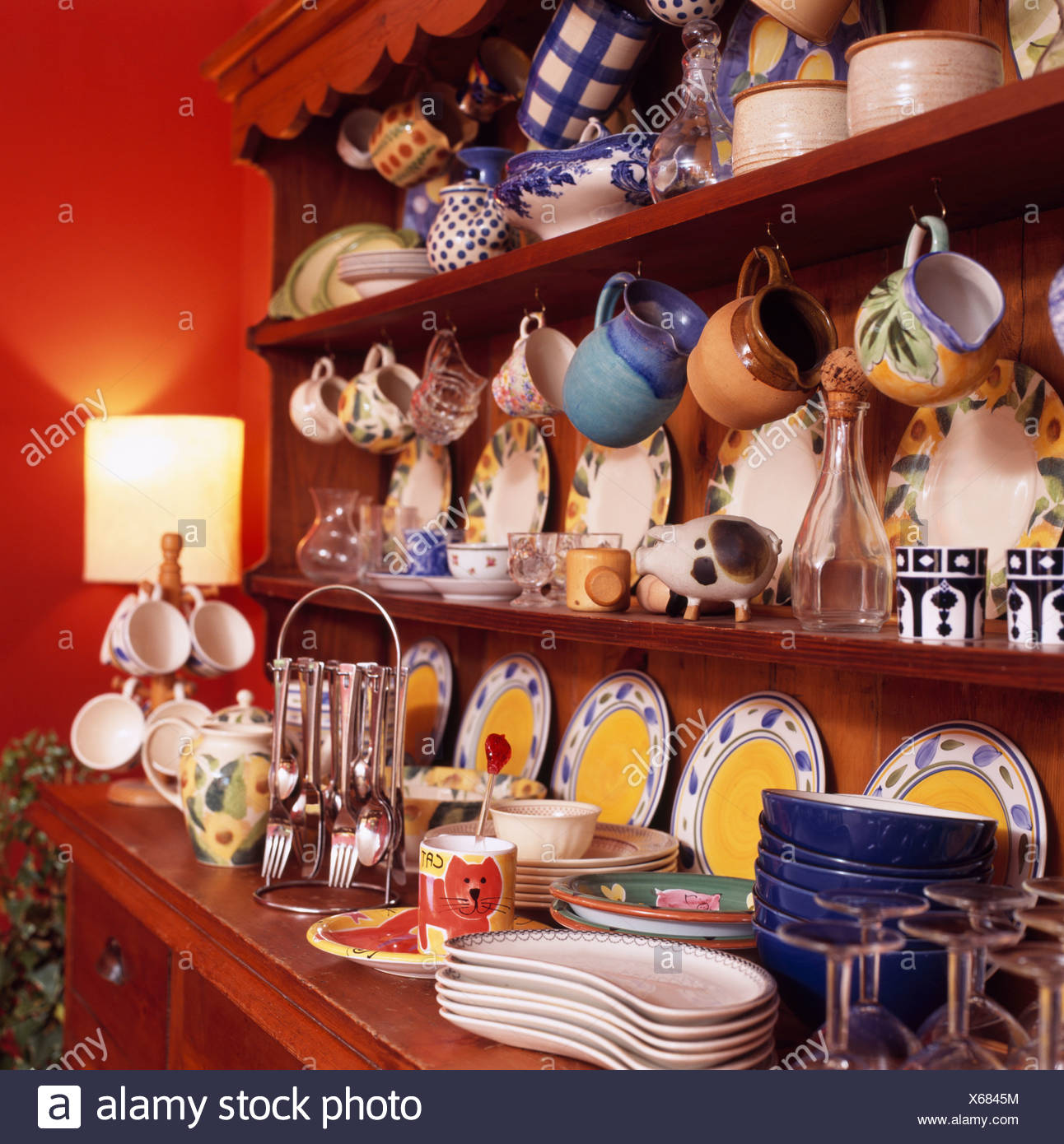 Dresser With Colourful Crockery On Shelves In Red Dining Room