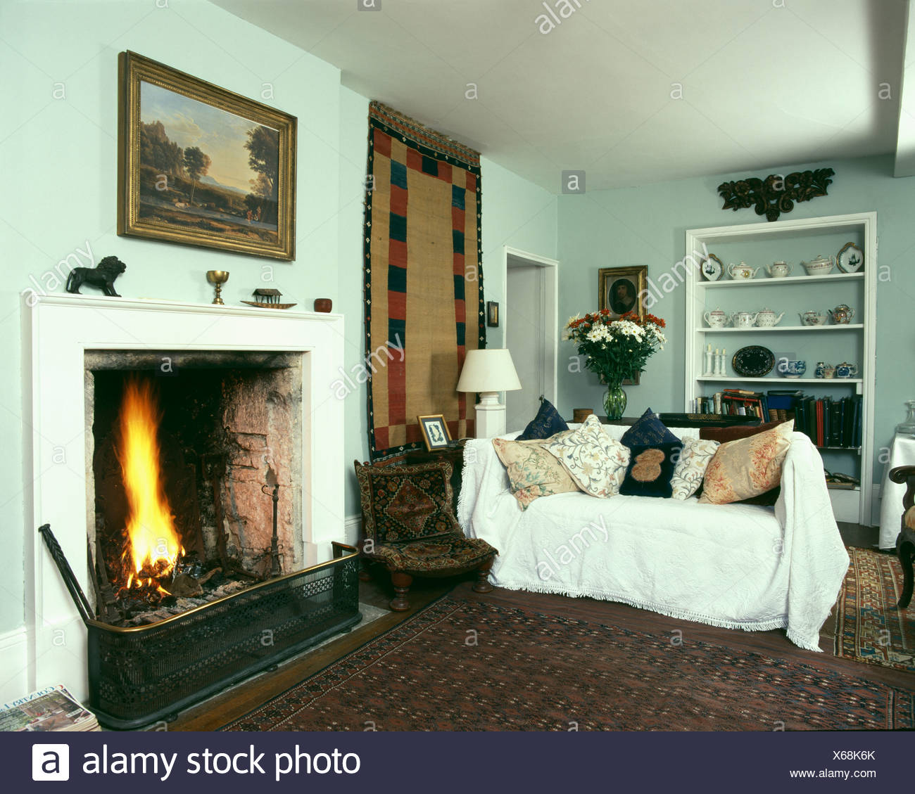 Country Livingroom With Fire Lit In Fireplace And Sofa With White