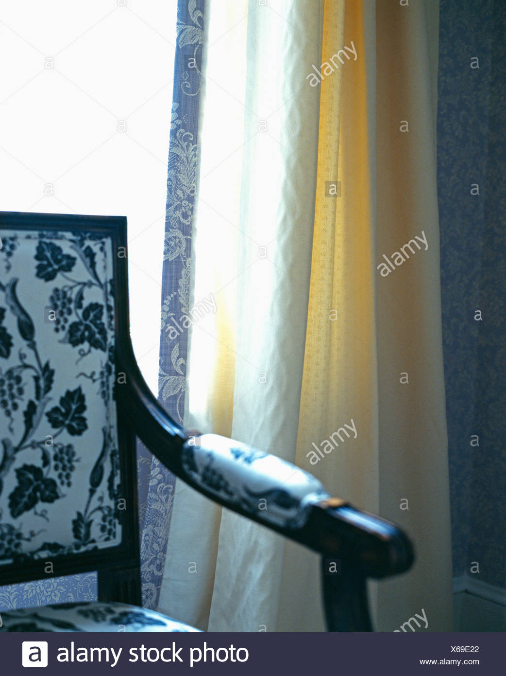 Close Up Of Upholstered Dining Chair Against Window With Cream Curtain Edged With Blue Patterned Fabric Stock Photo Alamy