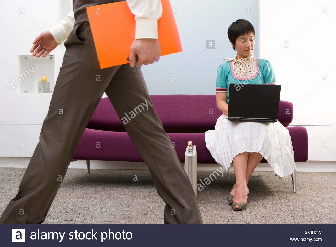 Young Woman Using Laptop Computer On Sofa Businessman Walking