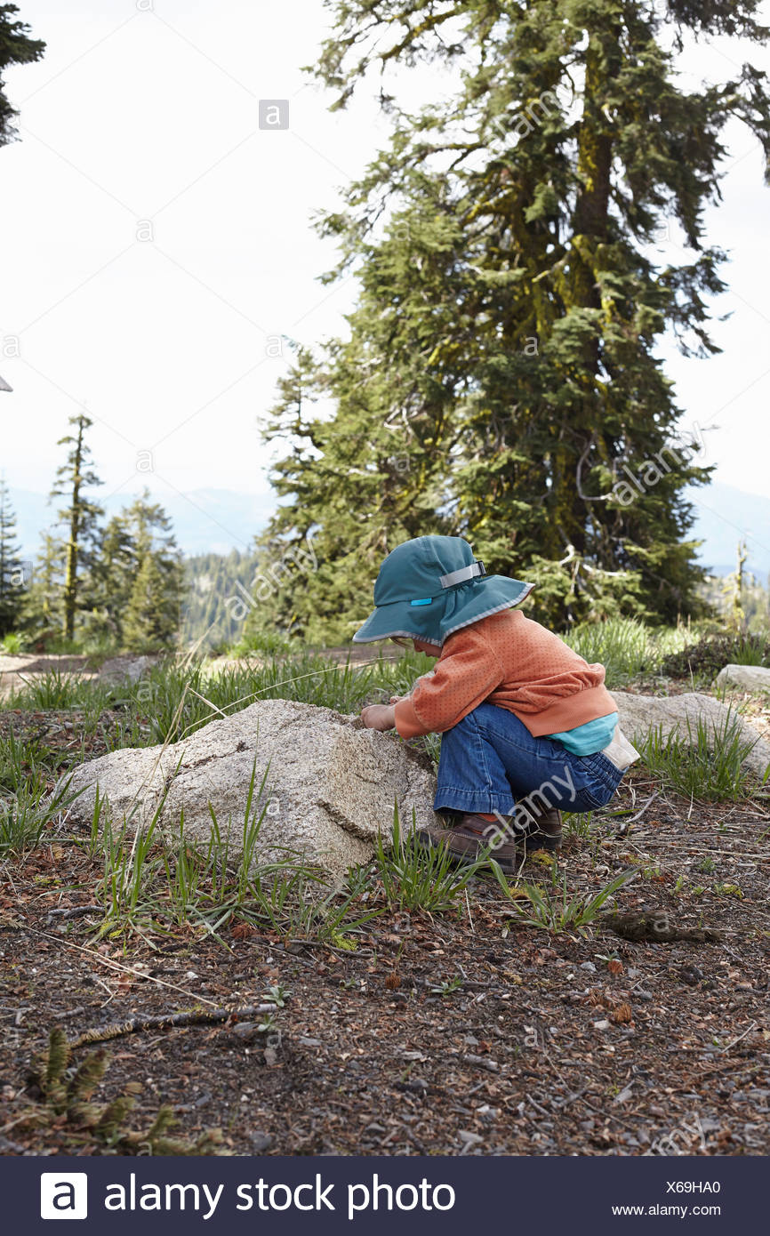 Toddler bending down to look at rock Stock Photo