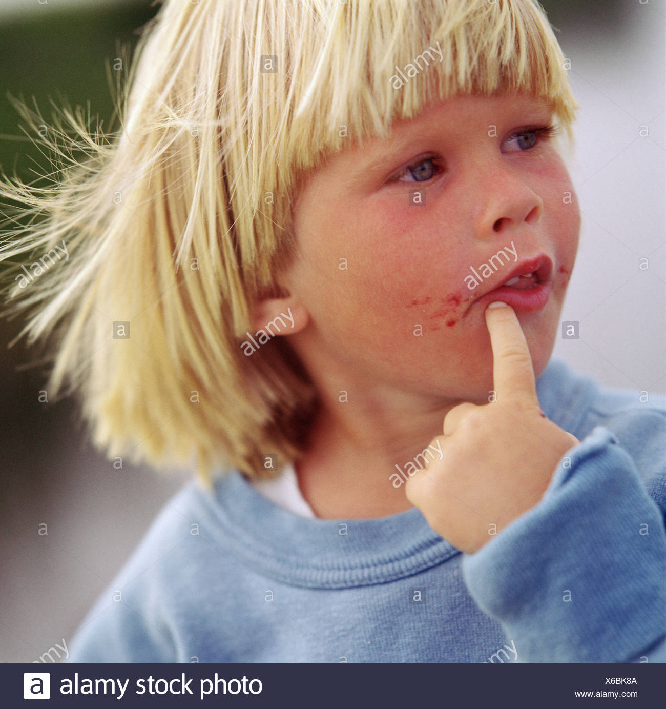 Close Up Of A Young Blonde Hair Boy With His Finger Near His Dirty
