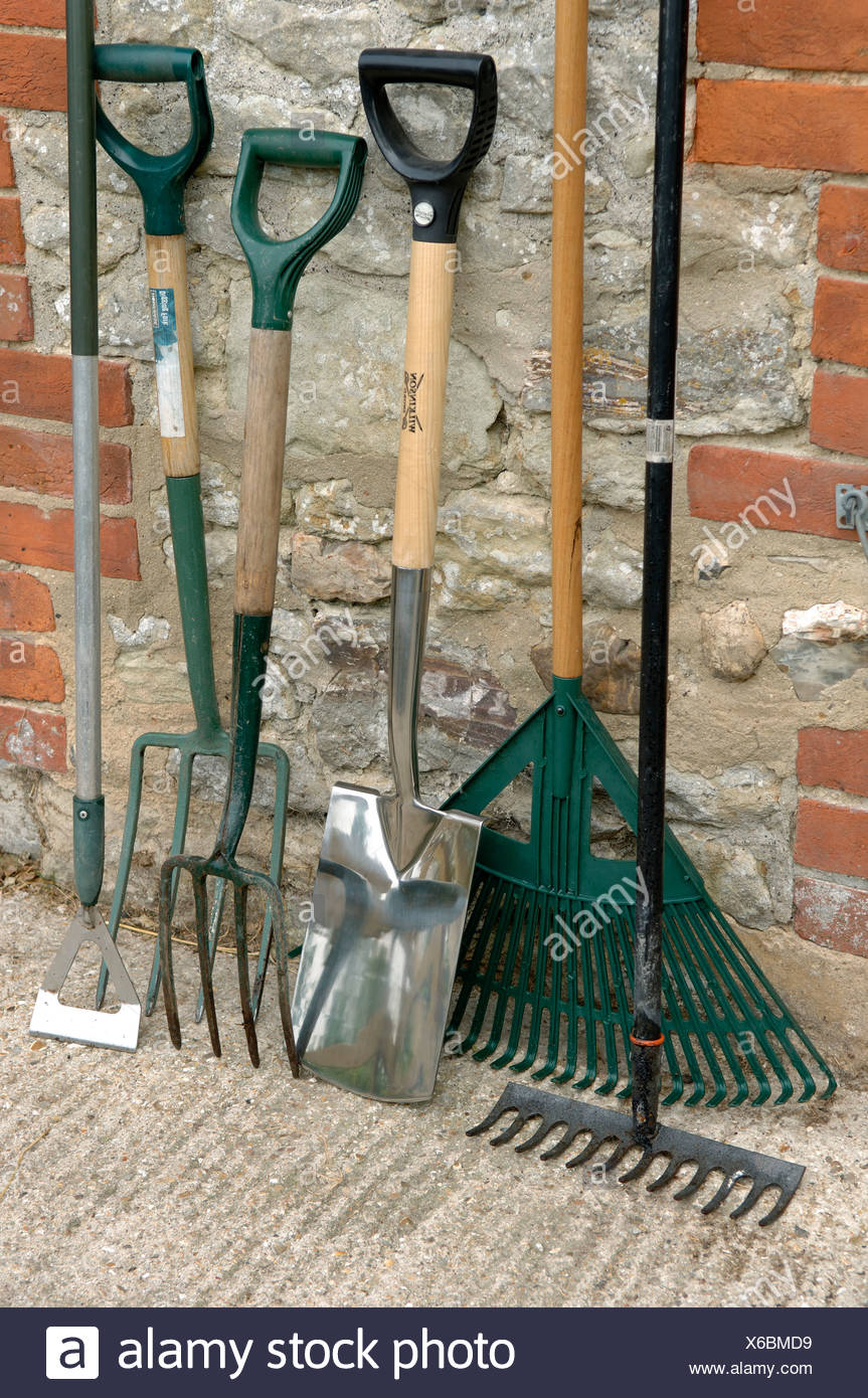 Garden Tools Spade Hoe Forks And Rakes Leaning Against An Outhouse Wall Stock Photo Alamy
