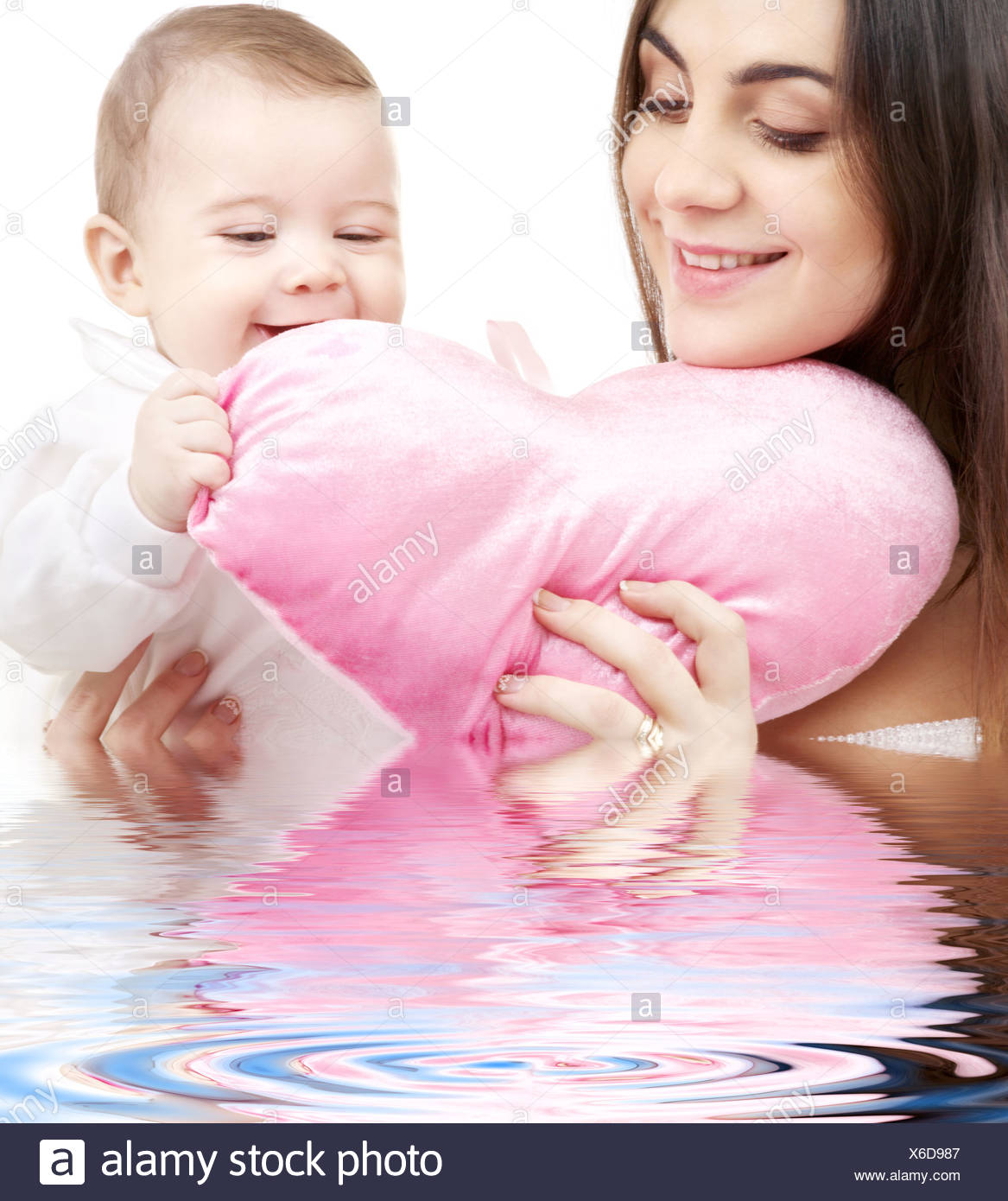 Happy Baby And Mama With Heart Shaped Pillow In Water Stock Photo