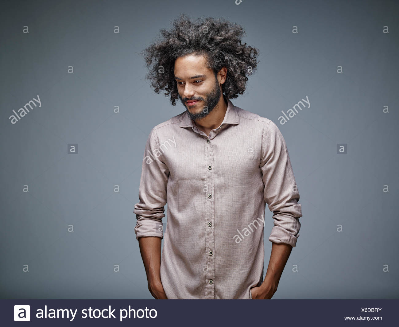 Portrait Of Smiling Young Man With Curly Brown Hair In Front Of Grey Background Stock Photo Alamy