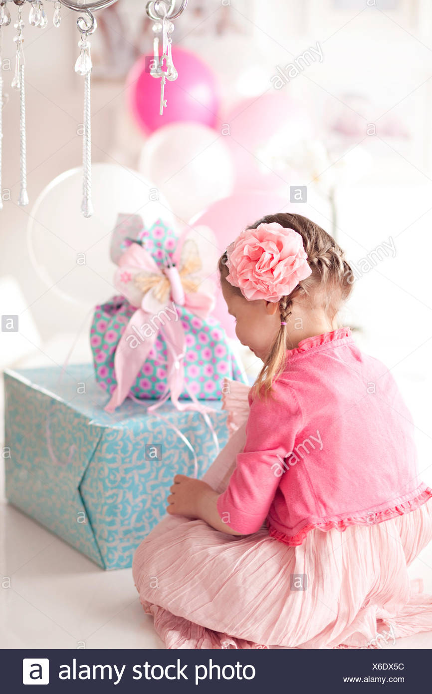 Girl sitting in front of a stack of birthday gifts Stock Photo