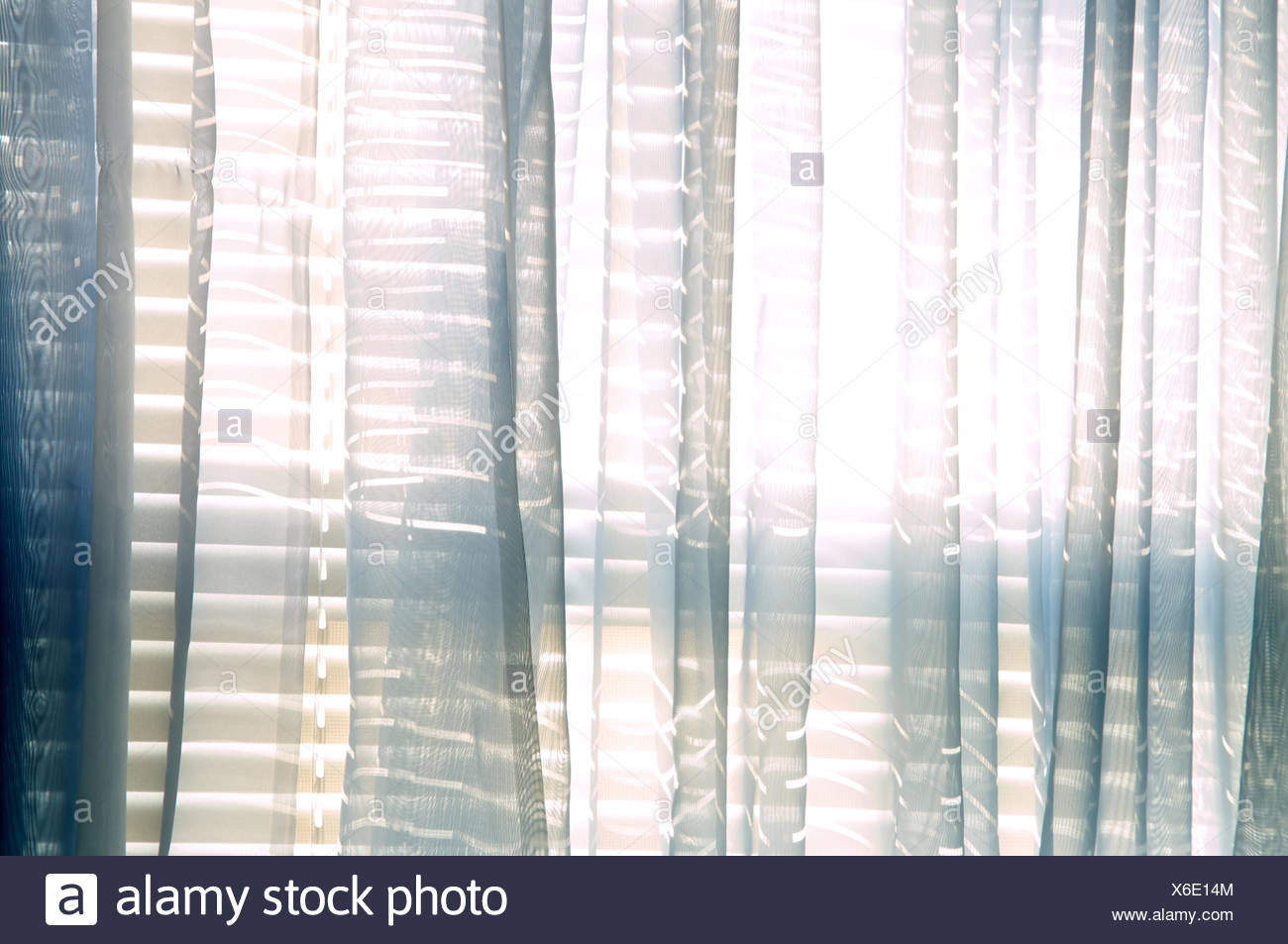 Bright Daylight Shines Through A Window Draped With Blue Sheer