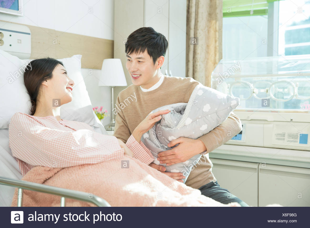 Harmonious couple holding their newborn baby at hospital room Harmonious couple holding their newborn baby at hospital room