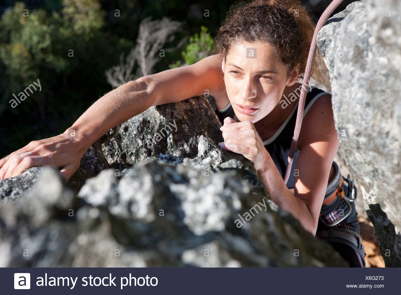 Young female rock climber moving up rock face Stock Photo