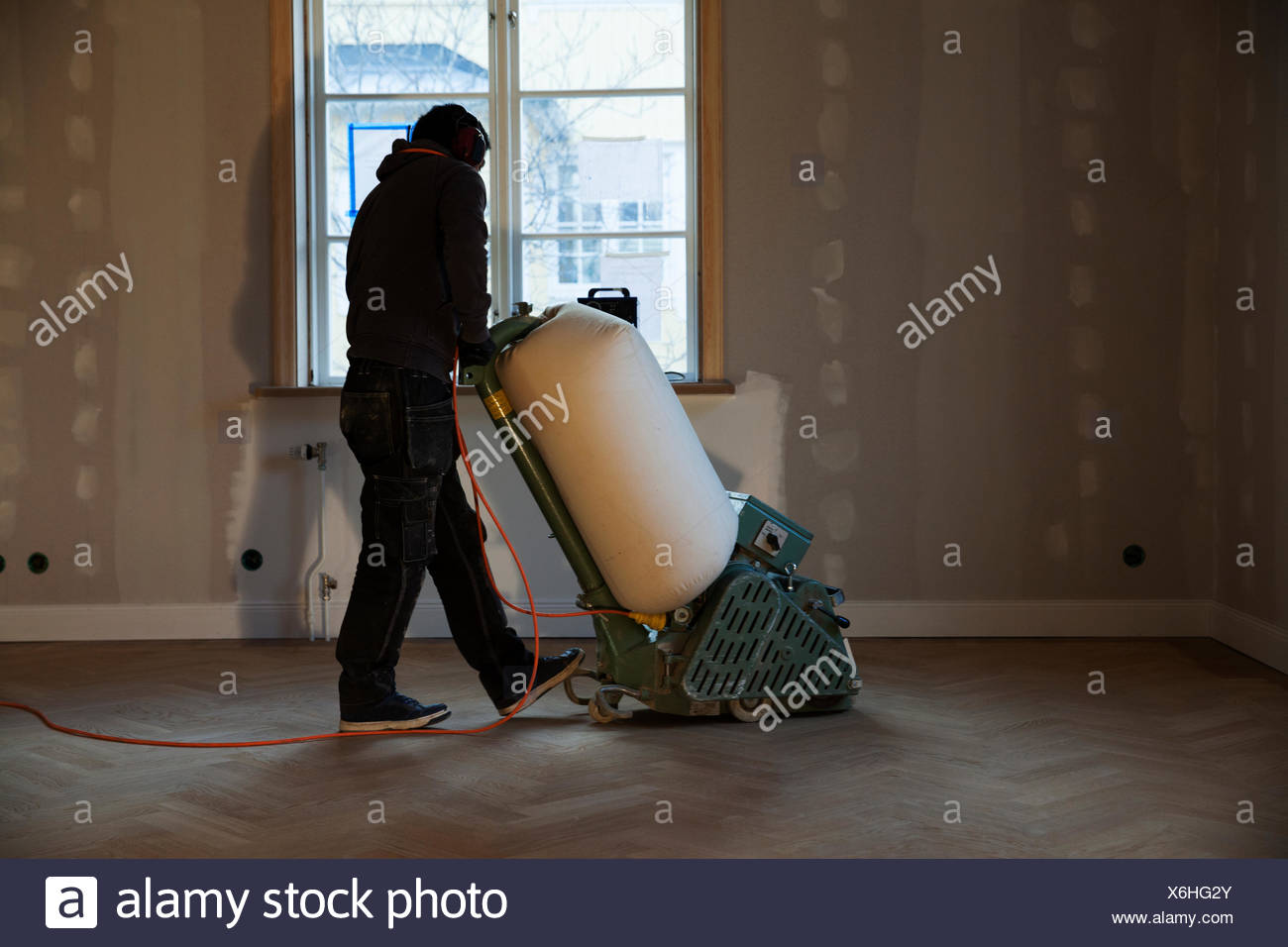 Man Cleaning Wooden Floor With Floor Polisher Stock Photo