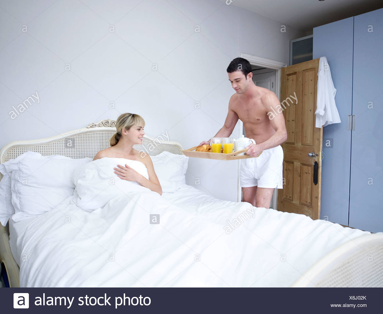 Жена порадовала мужа. Парень приносит завтрак в постель. Мужчина приносит кофе в постель. Мужчина приносит кофе в пастель. Мужчина несет кофе в постель.
