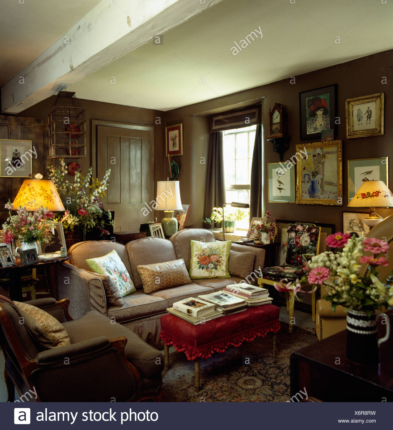 Lighted Lamps And Pictures On Walls Of Brown Country Livingroom With Low Ceiling And Comfortable Furniture Stock Photo Alamy