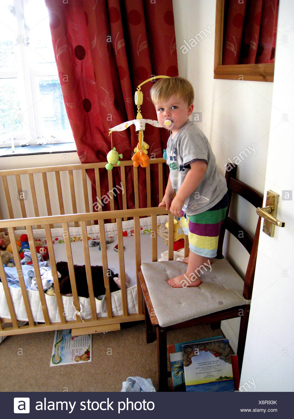 Toddler On Chair After Climbing Out Of Crib Stock Photo 279565879