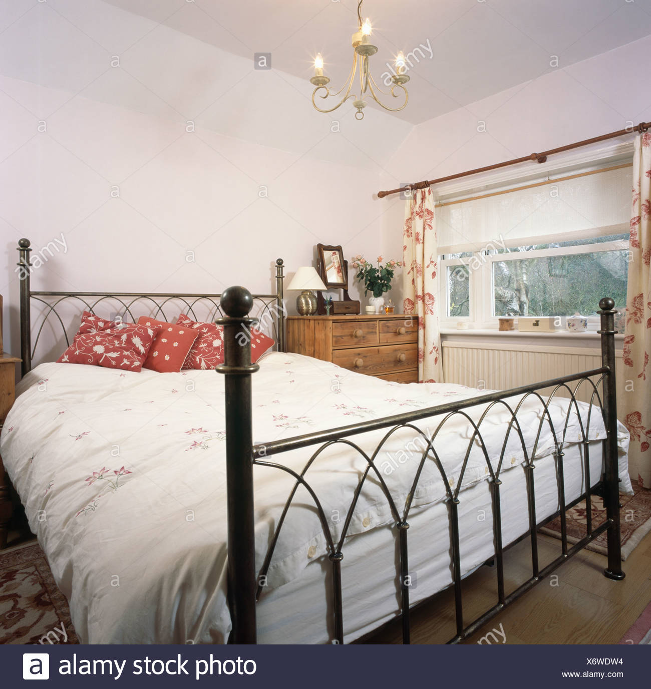 Black Cast Iron Bed With Red Cushions And White Bedlinen In