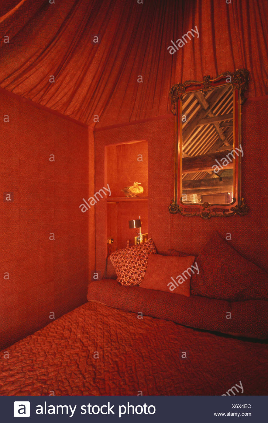 Mirror Above Bed In Seventies Bedroom With Red Walls And
