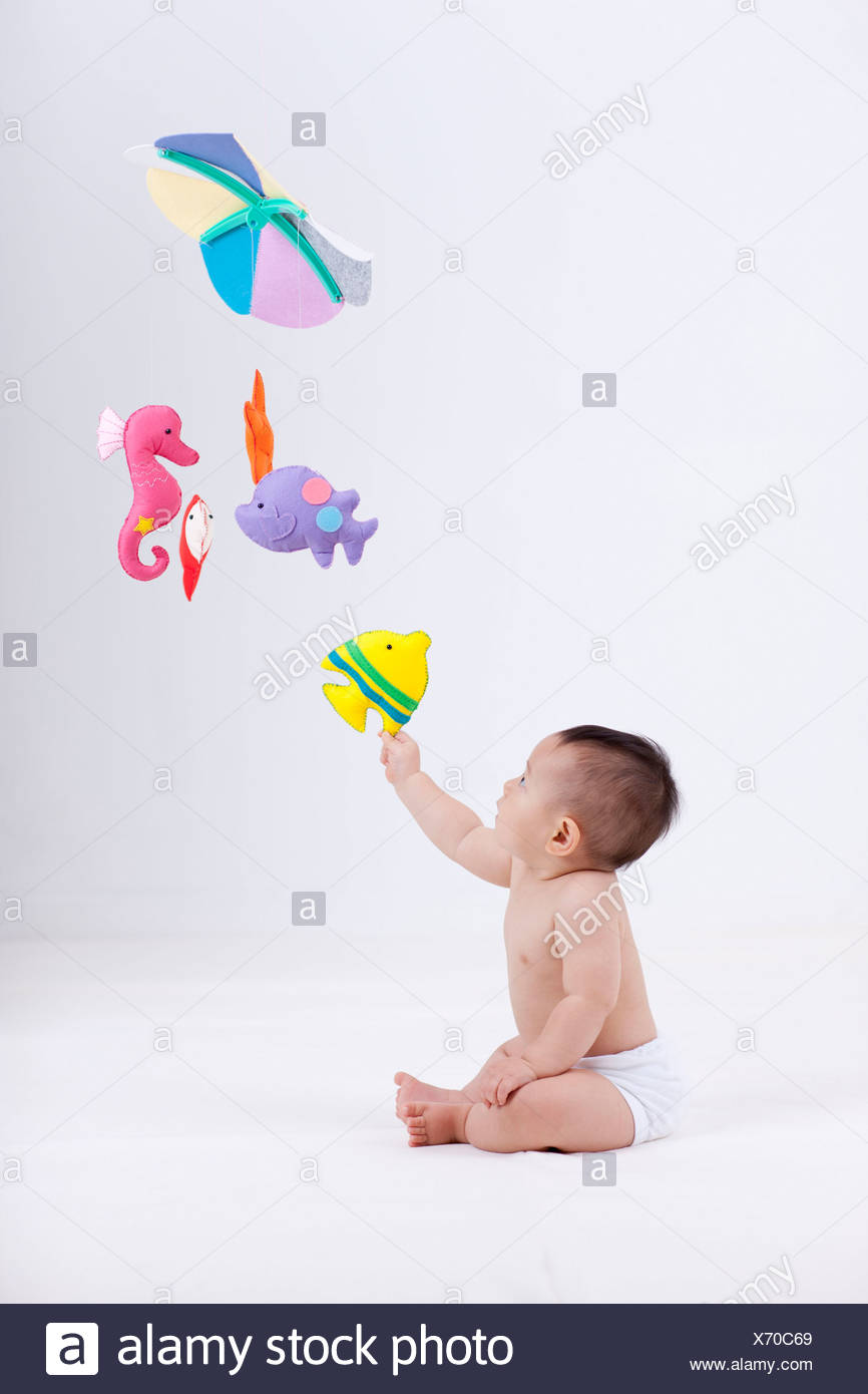 A Baby In Diaper With Mobiles Hanging In The Ceiling Stock Photo