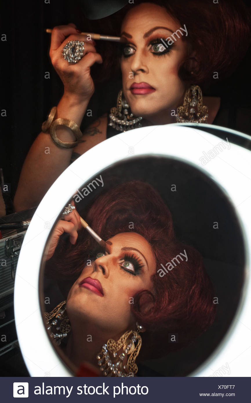 Cross Dressing Man Putting On Makeup At A Mirror Stock Photo