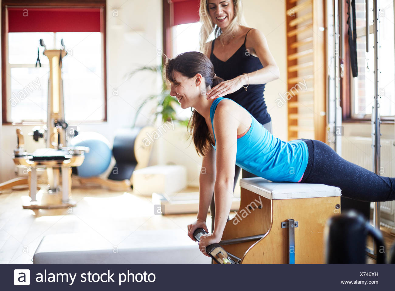 Young female student pushing up from combo chair in pilates gym Stock Photo