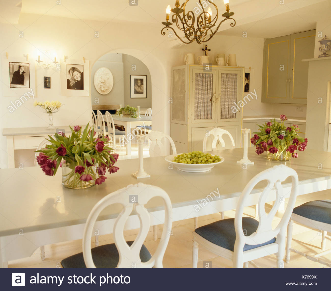 Red Tulips In Glass Vases On White Table With White Chairs