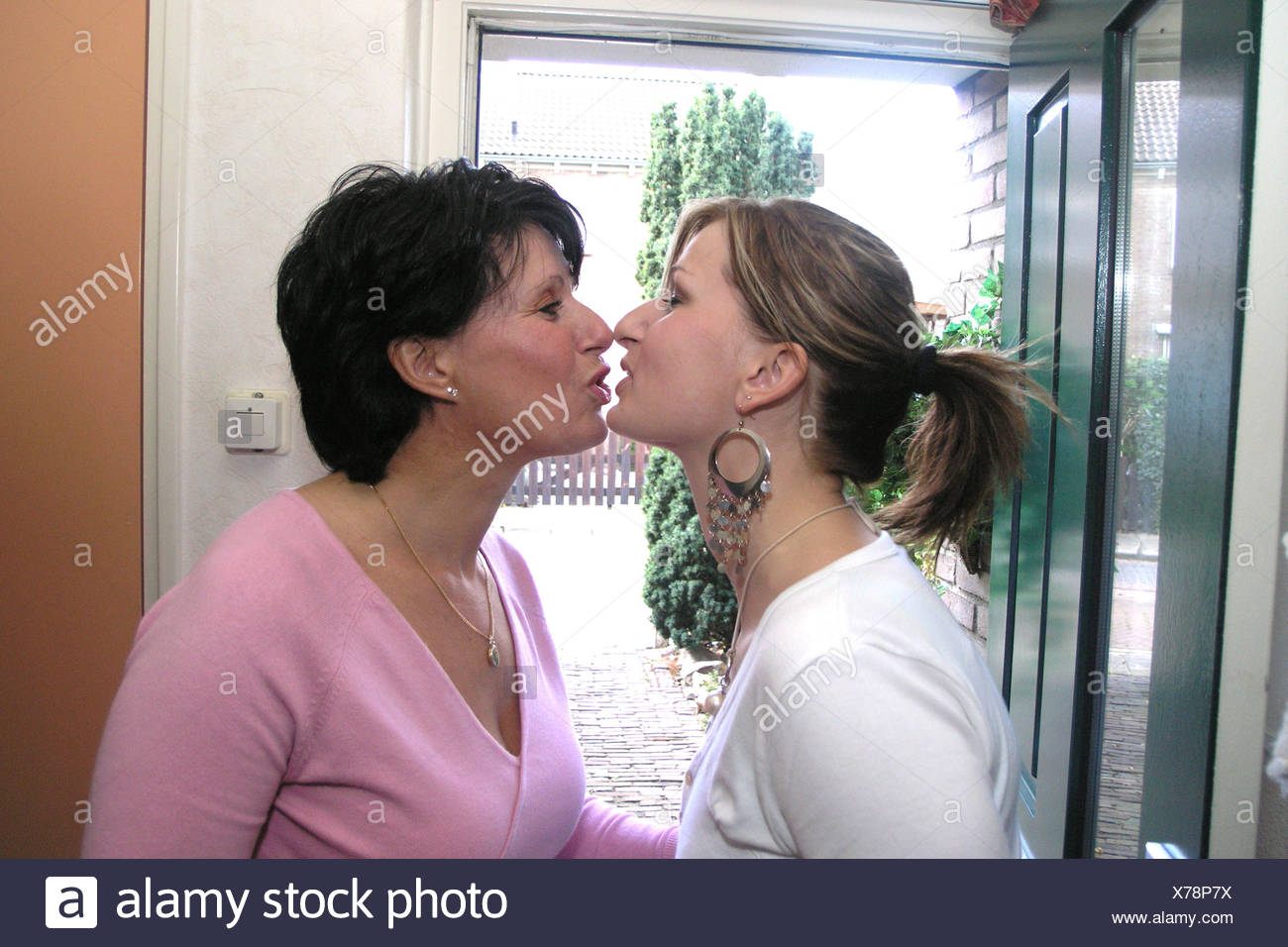 Daughter kissing mother front door - Stock Image.