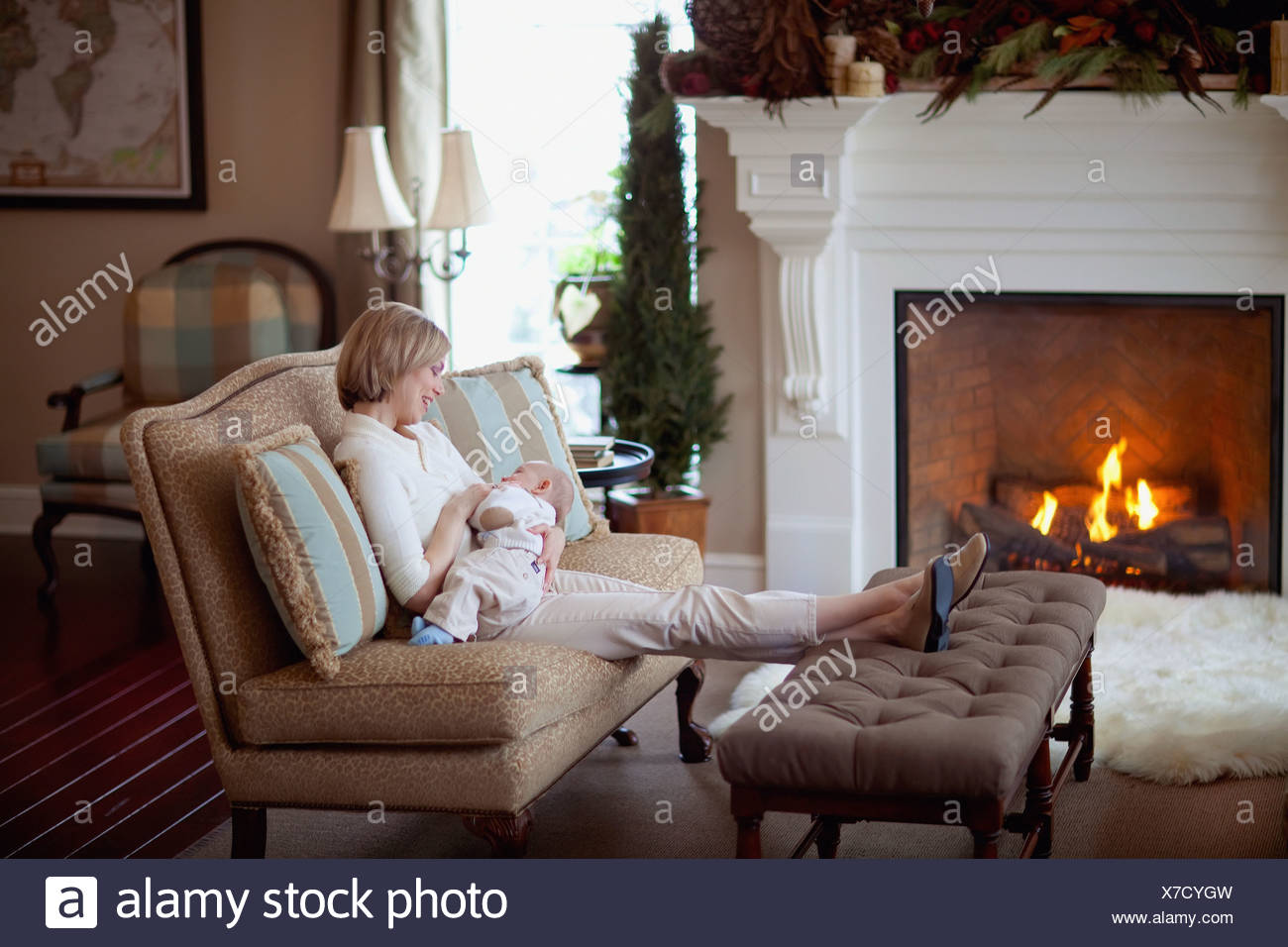 A Mother Holding Her Baby By A Fireplace In The Living Room