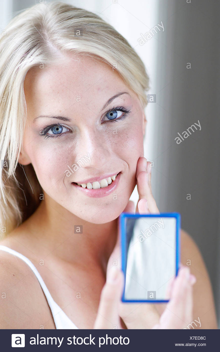 Female Long Blonde Hair Wearing A White Vest Lightly Rubbing Her