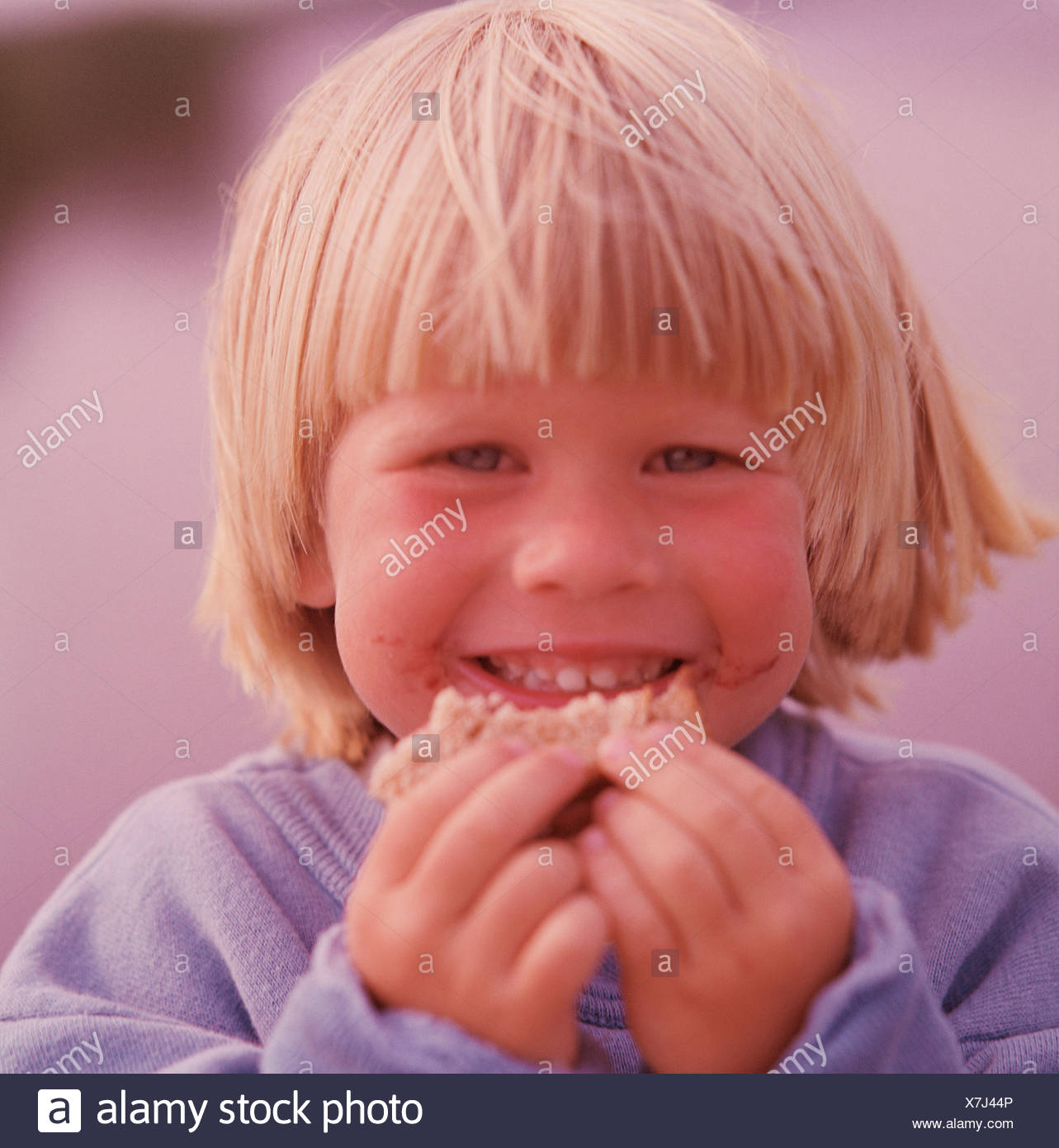 Close Up Of A Blonde Hair Blue Eyed Boy Eating Hand Food Stock